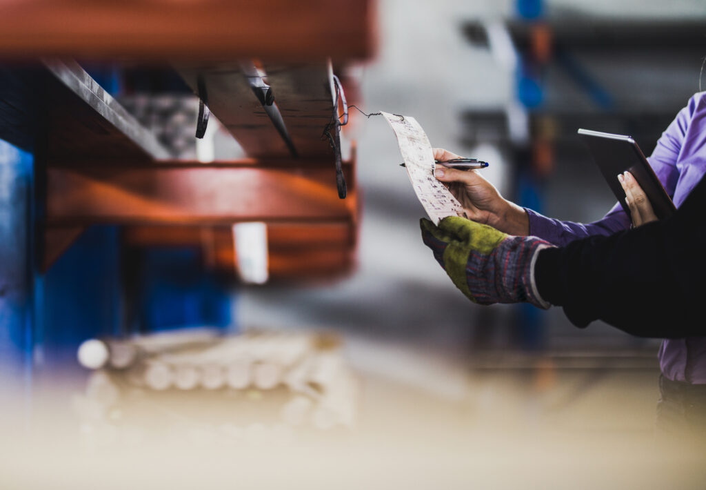 Unrecognizable inspector and manual worker analyzing labels in aluminum mill.